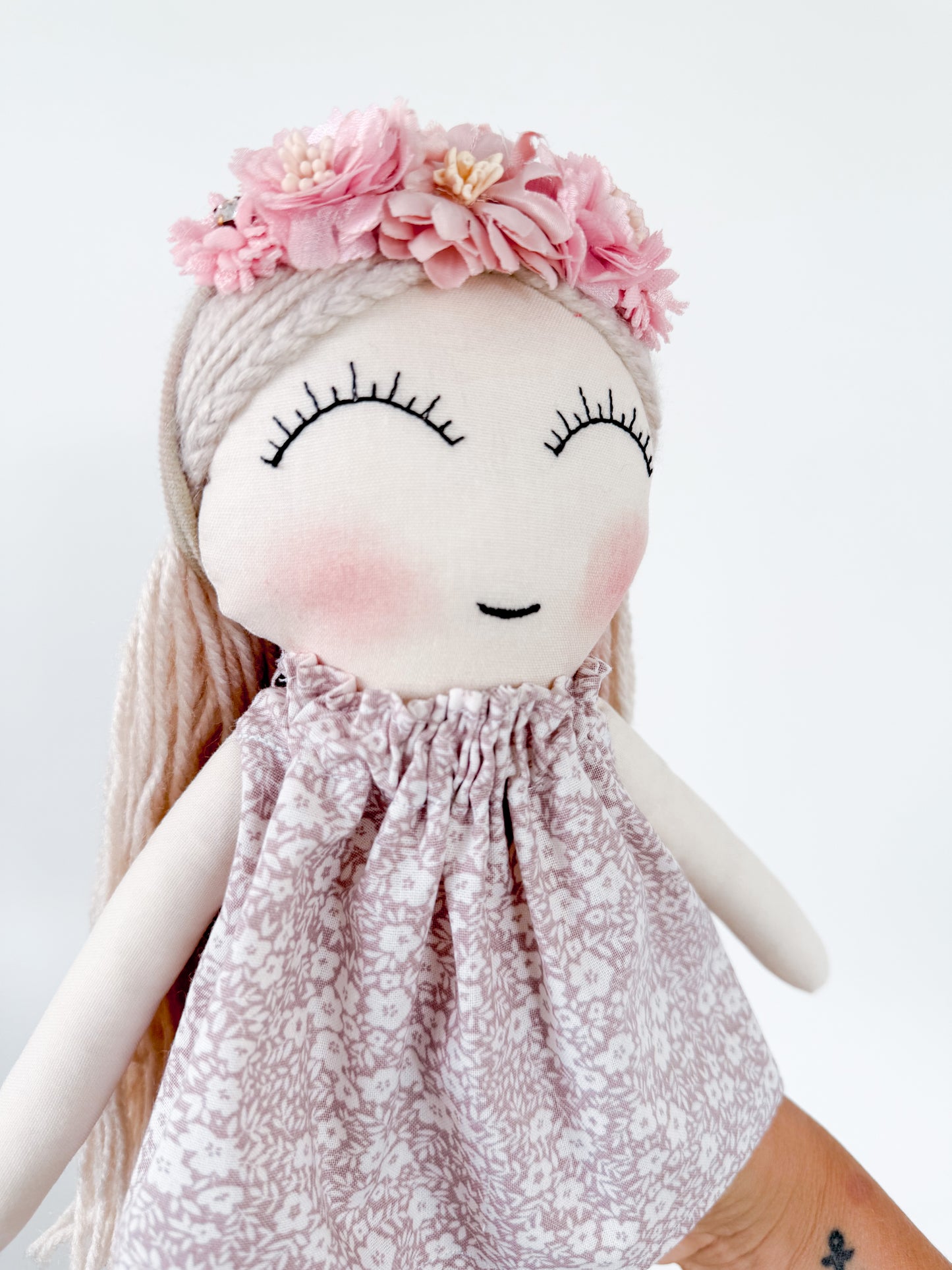 Doll with floral headband and patterned dress on a white background