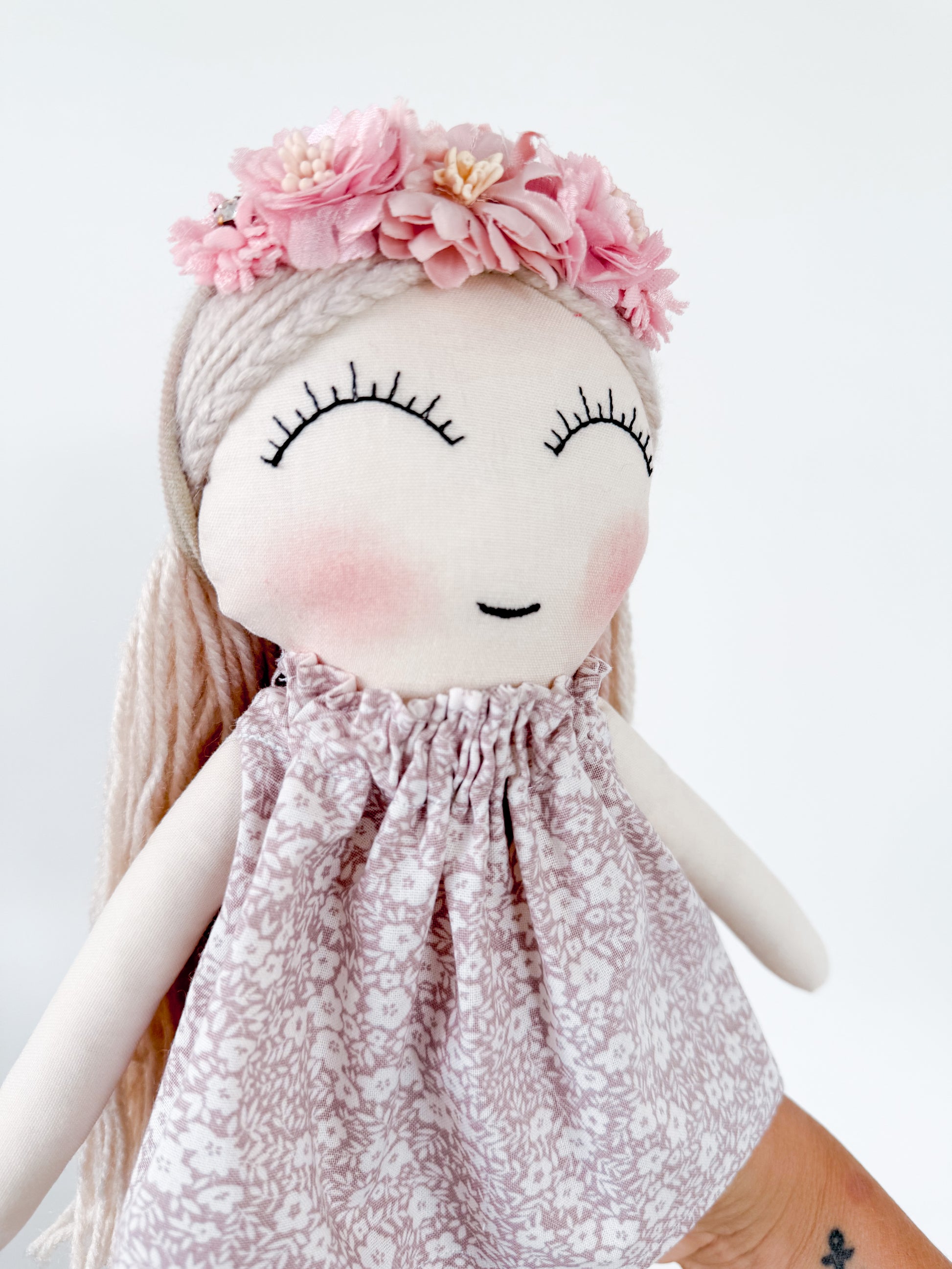 Doll with floral headband and patterned dress on a white background