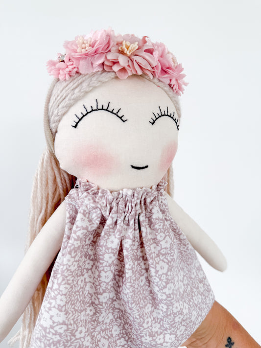 Doll with floral headband and patterned dress on a white background